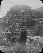 A priest sitting at the entrance to a cell on Skellig Michael