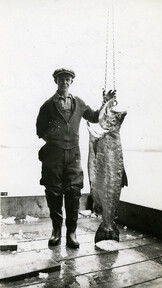 View of foreman Angus McDonald with a Co-op salmon at Pacific Coast Fishermen's Union (P.C.F.U.) fish buying camp at Stuart Island Landing, B.C