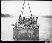 A group of children hoisted by a crane on board HMAS AUSTRALIA II