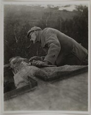Akseli Gallen-Kallela on the town of TarvaspÃ¤Ã¤ working on a dragon-shaped gargoyle, 1927; photograph 2.