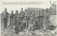 Northumberland Fusiliers wearing German helmets and gas-masks captured at St Eloi. Official photograph