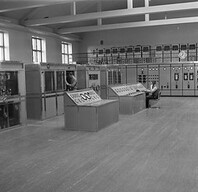 Yle's radio transmission unit in Lahti radio station, 1930's. View of transmitter hall showing units with water cooled tubes and control desk of 150 kw Marconi transmitter. Ac distribution panels in background.