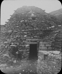 A priest sitting at the entrance to a cell on Skellig Michael