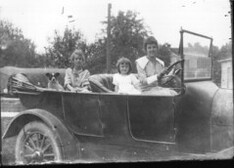 Woman with two children and dog in automobile n.d.