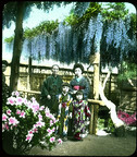 Family in traditional attire having portrait taken in garden against fence.