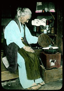 Old woman in shed heating substance in black pot.