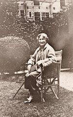 Eleanor Hull, full-length portrait seated in chair, in a garden with a book and a cane