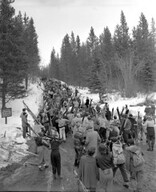 Crowds of skiers climbing hill