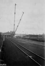 Steam derrick. Pressure treating plant at end of "N.G." tracks. Flat car load of ties at right center.