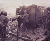 A wounded American soldier is loaded into a medic half-track