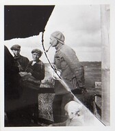 Akseli Gallen-Kallela with a pipe in his mouth, sculptor Alpo Sailo (the hand with a hammer on the left) and workers on the tower of TarvaspÃ¤Ã¤, 1927.