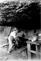 Paddy Flynn, chief clerk, Dept. of Public Works, cooking over open fire, kitchen of camp (to find site of Spit Bridge) in rock shelter, Middle Harbour