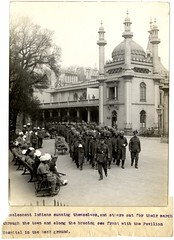 Convalescent Indians sunning themselves, and others out for their march through the town and along the bracing sea front with the Pavilion Hospital in the background [Brighton, England]. Photographer: H. D. Girdwood.