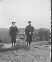 "Louie's arrival at Hodder. Two boys smiling wearing short pants standing at either side of an ornamental vase"