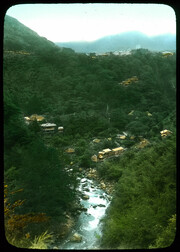 Houses in the woods, river in foreground.