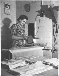 Vanice Sullivan, wife of the Station Master, testing the heat of her iron, Drouin, Victoria, ca. 1944