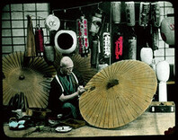 Man painting parasols; painted lanterns in background.