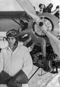 Bush pilot Charles (Cy) Becker standing in front of airplane