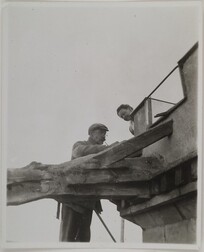Akseli Gallen-Kallela on the tower of TarvaspÃ¤Ã¤ working on a dragon-shaped gargoyle with his wife Mary watching, 1927.