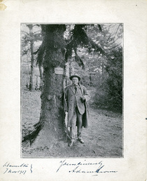 Adam Brown (1826-1926) standing against the tree that was planted in his honour in 1859. 1915-05-05