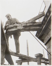Akseli Gallen-Kallela on the tower of TarvaspÃ¤Ã¤ working on a dragon-shaped gargoyle, 1927; photograph 3.
