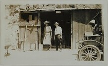 Two men in a doorway and another man by a car, all wearing hats, probably in Chihuahua, Mexico, 1925.