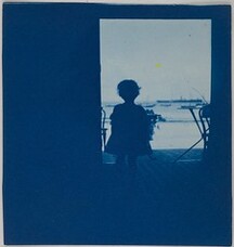 Child standing in the doorway of a seashore house.