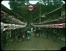 Crowd-filled street lined with banners and lanterns.