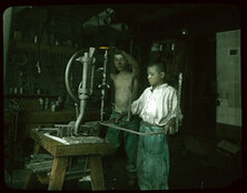 Two boys using drill press.