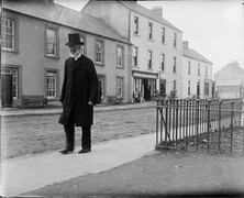 Man with beard and top hat walking along a road (in Bundoran)