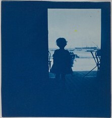 Child standing in the doorway of a seashore house.
