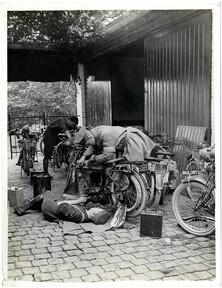 A dispatch rider [of the Indian Corps] repairing motor cycle [Merville, France]. Photographer: H. D. Girdwood.