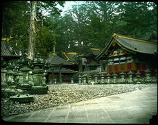 Group of buildings set among trees; ornamental stone wall in front.