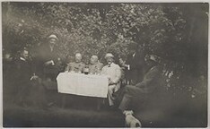 Akseli Gallen-Kallela (standing on the left), Knut Boije (sitting next to him) and some other men at a garden table; photograph 3.