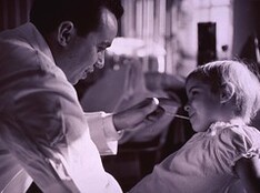 Physician taking temperature of young patient