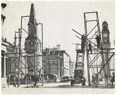 View north down St John Street Launceston from Paterson Street corner, with men erecting V day arch.  Photograph by Burrows (1946)