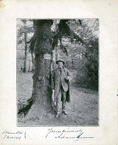Adam Brown (1826-1926) standing against the tree that was planted in his honour in 1859. 1915-05-05