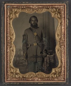 [Unidentified African American soldier in Union infantry sergeant's uniform and black mourning ribbon with bayonet in front of painted backdrop]  (LOC)