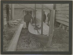 Manninen making a rowing boat for the GallÃ©ns with Jorma and Kirsti GallÃ©n watching, in Ruovesi, in the 1900Â´s; print 1 of the photograph.