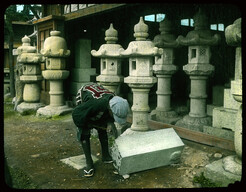 Man beginning to carve lantern from block of stone.