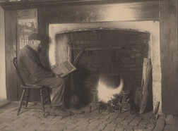 Man reading by fire, date unknown