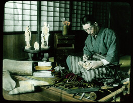 Man carving ivory statue of mother and child.