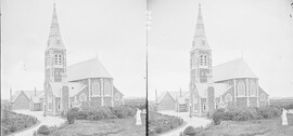 Modern Gothic church in open country, square tower and spire, statue of warrior with harp in foreground