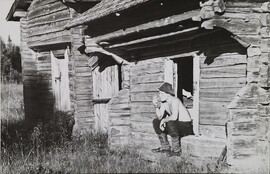 Man smoking his pipe while sitting on the steps to a traditional timber barn