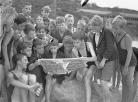 Stewart House boys looking at comics from a Sunday paper, South Curl Curl Beach, by Sam Hood, 10 January 1935