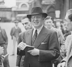 "Genial toff, with monacle, holds passport aloft" is likely Richard Tauber