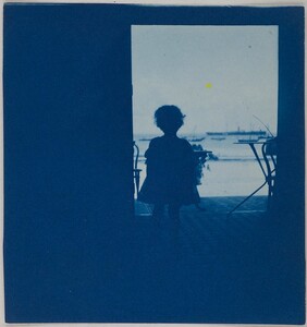 Child standing in the doorway of a seashore house.