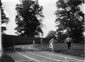Runners on track with judge at high school track meet 1912