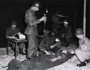 A casualty being treated by a doctor and two aidmen in the division surgery tent, 7 Dec. 1951 U.S. Signal Corps.